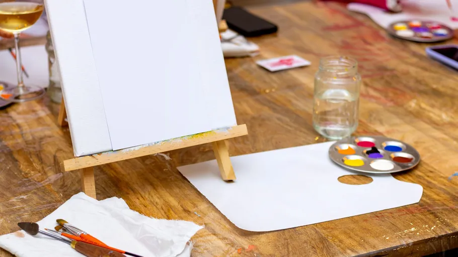 Blank canvas on easel with paints nearby.