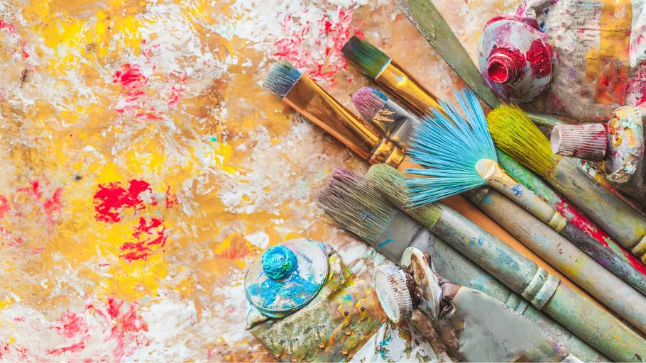 Pinsel und Tuben auf bunter Palette.