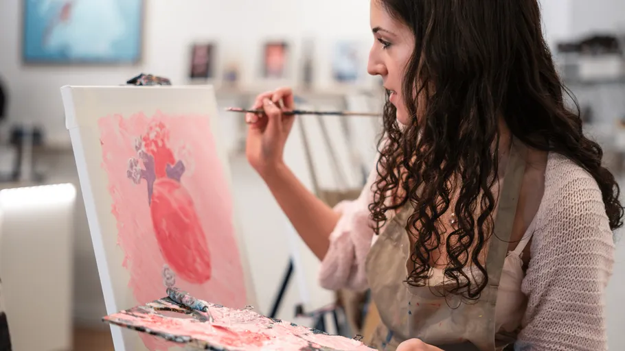 Woman painting on canvas in art studio.