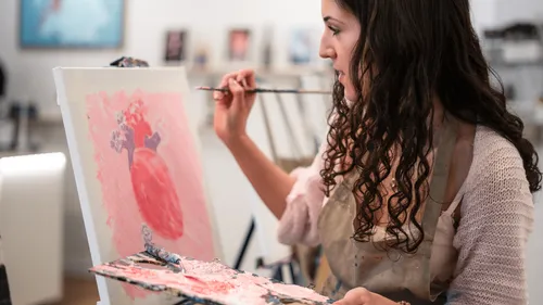 Woman painting heart on canvas in studio.