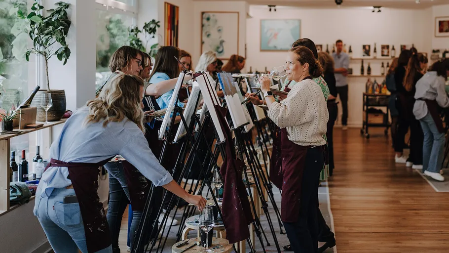 Group painting while drinking wine in studio.