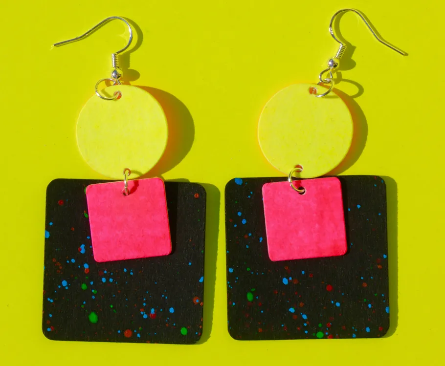 Colorful geometric earrings on yellow background.