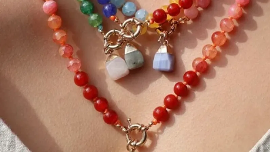 Layered beaded necklaces with gemstone pendants.