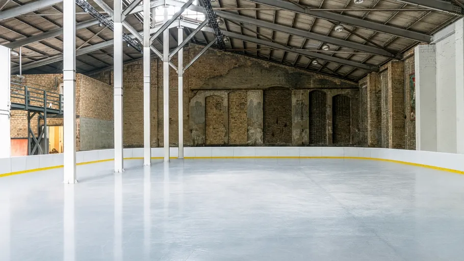 Empty indoor ice rink in industrial building.