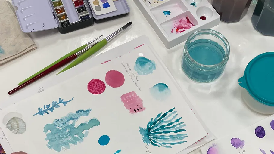 Aquarellfarben und Papier mit blauen Designs.