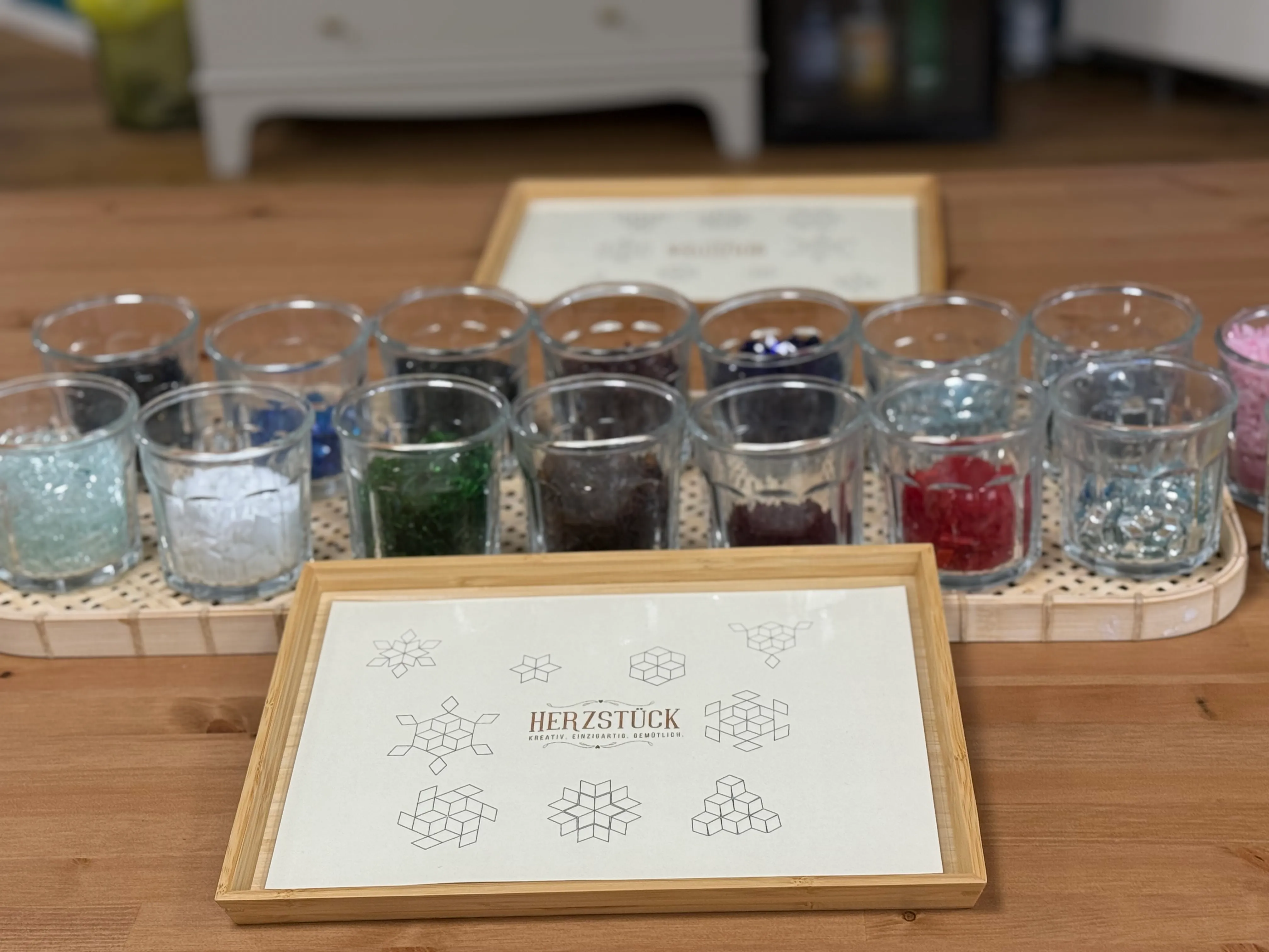 Glasgefäße mit bunten Steinen auf Tisch.