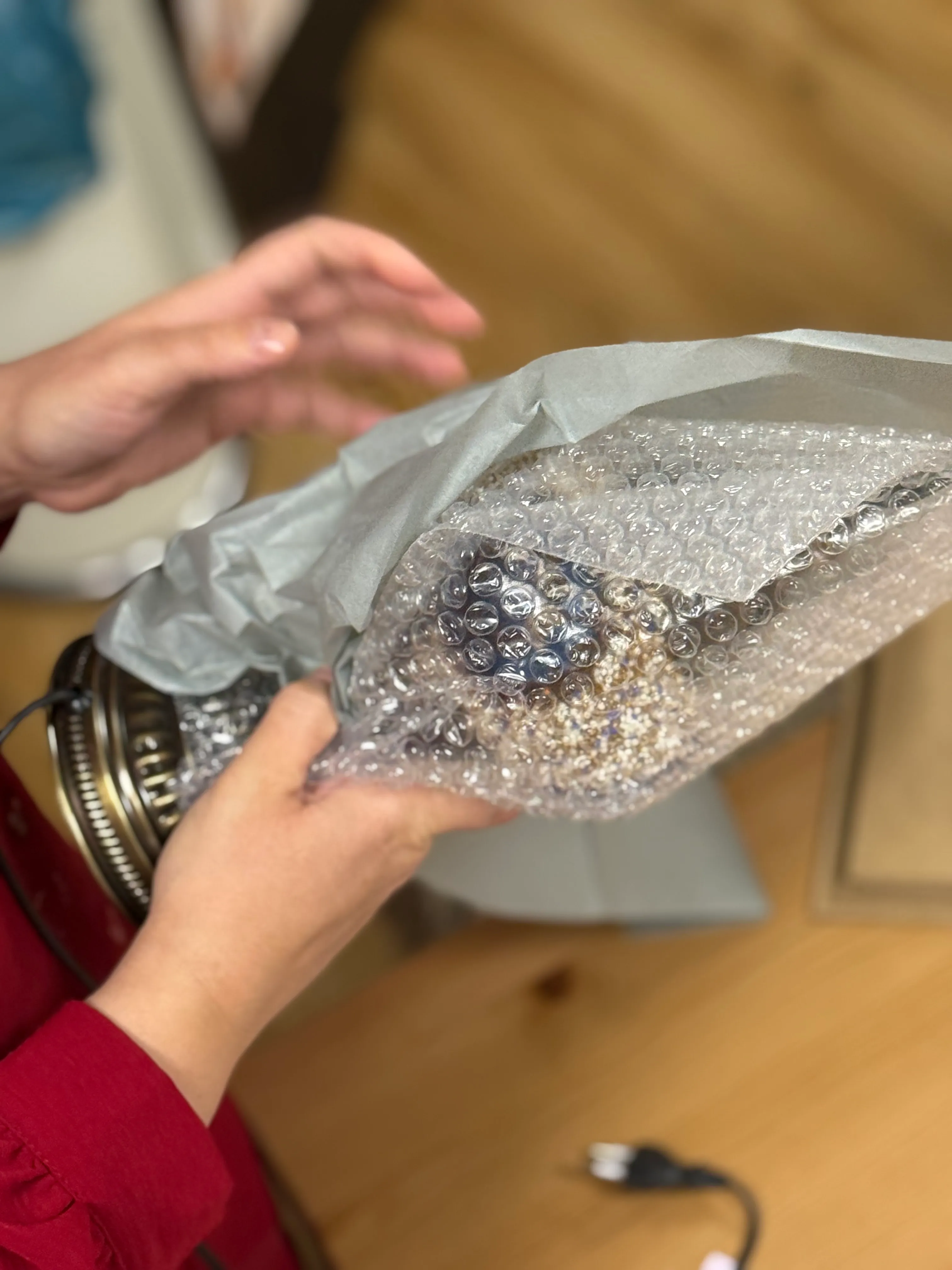 Hände packen Luftpolsterfolie auf Tisch aus.