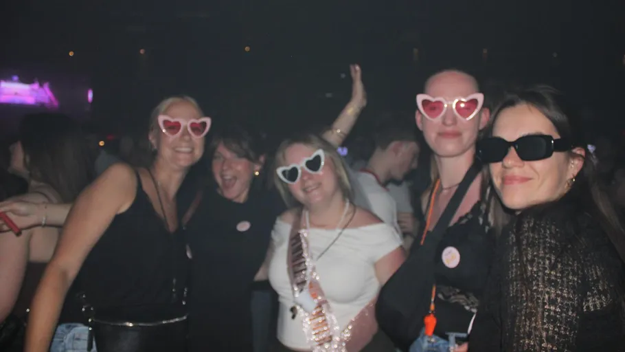 Gruppe Frauen mit Herzbrillen auf Party.