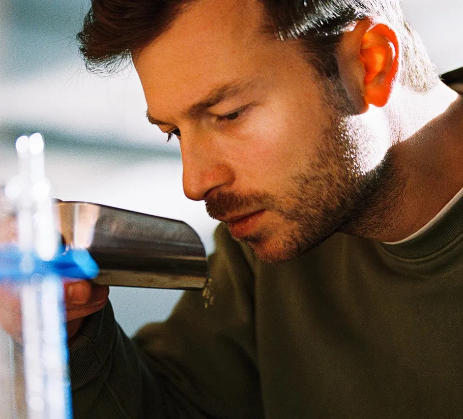 Man smelling metal container in bright room.