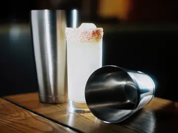Glass with sugar rim between two metal shakers.