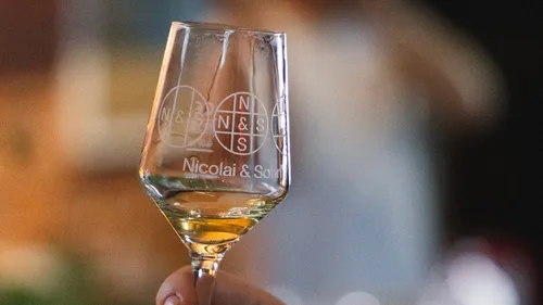 Wine glass with logo held indoors.