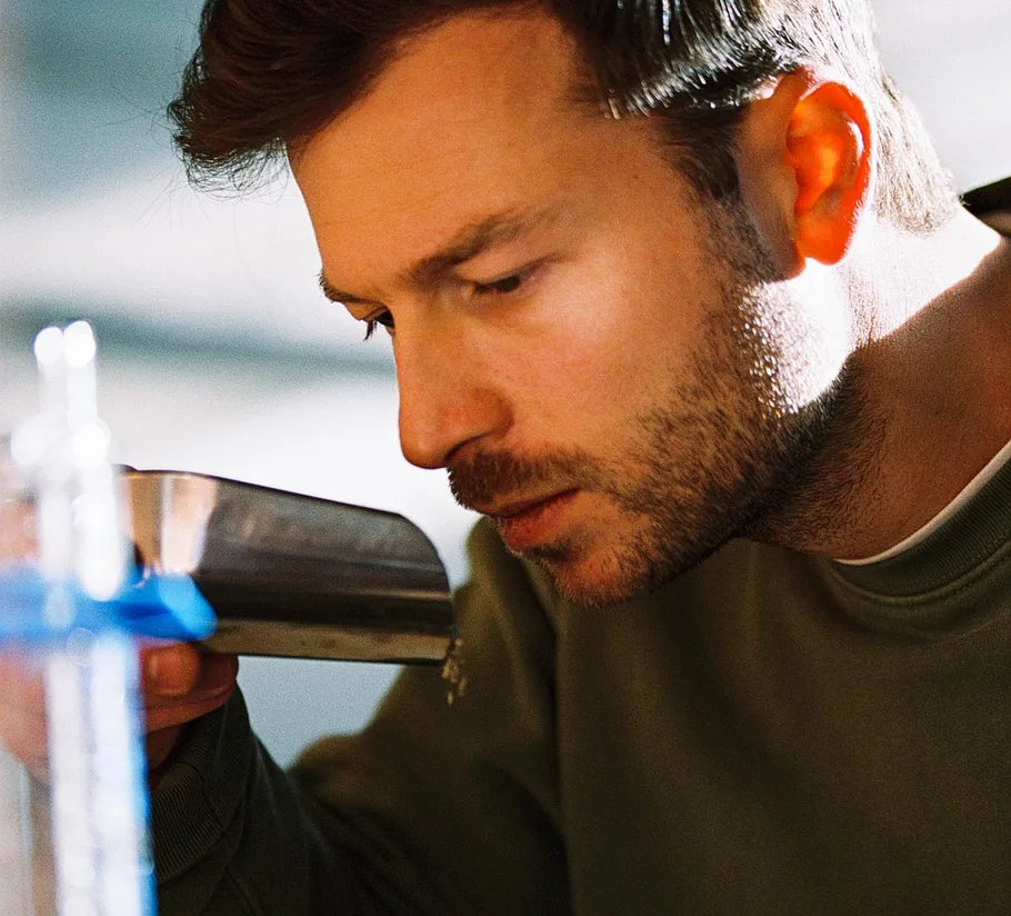 Man smelling ground coffee in a kitchen.