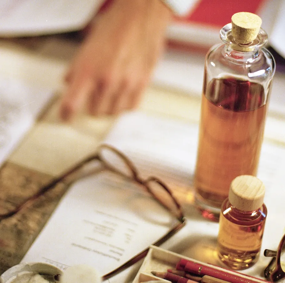Bottles on desk with papers and glasses.