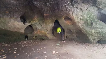 Person crawling out of rock cave.