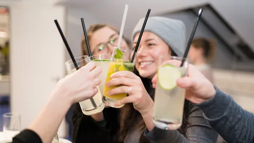 People toasting with beverages, indoor gathering.