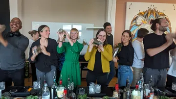 People shaking cocktail shakers in a group setting.