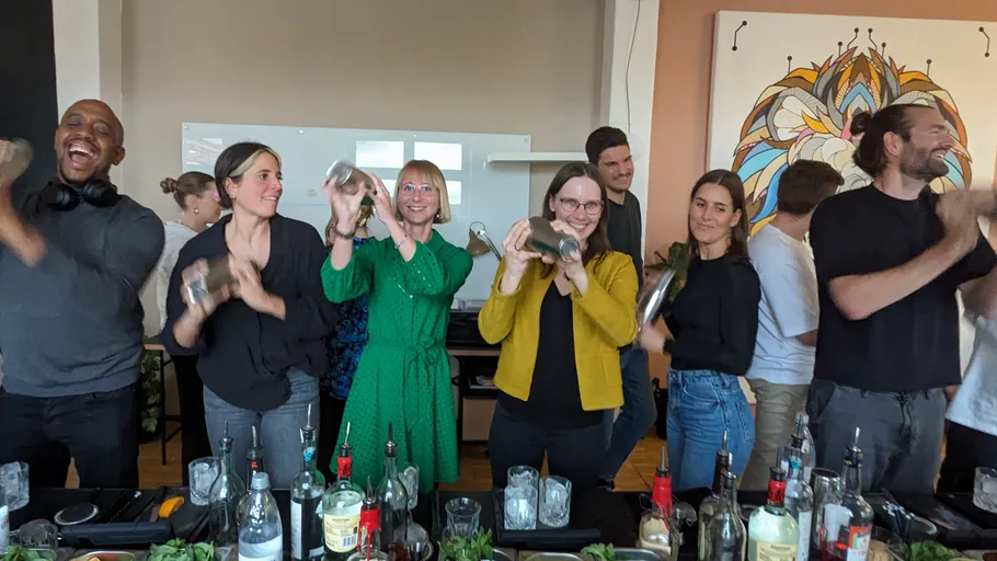 People shaking cocktail shakers in a group setting.