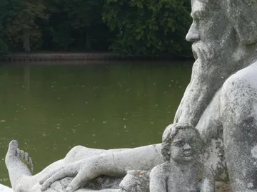 Skulptur von einem alten Mann mit Kind am Wasser.