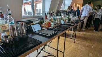 Bar setup with bartending tools and people mingling.