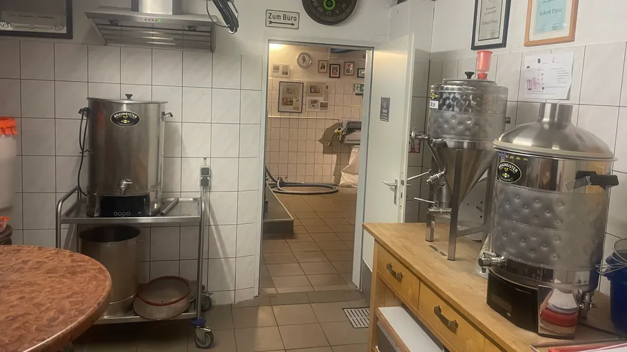 Brewery equipment in a white-tiled room.