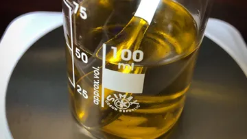 Beaker containing yellow liquid on scale.