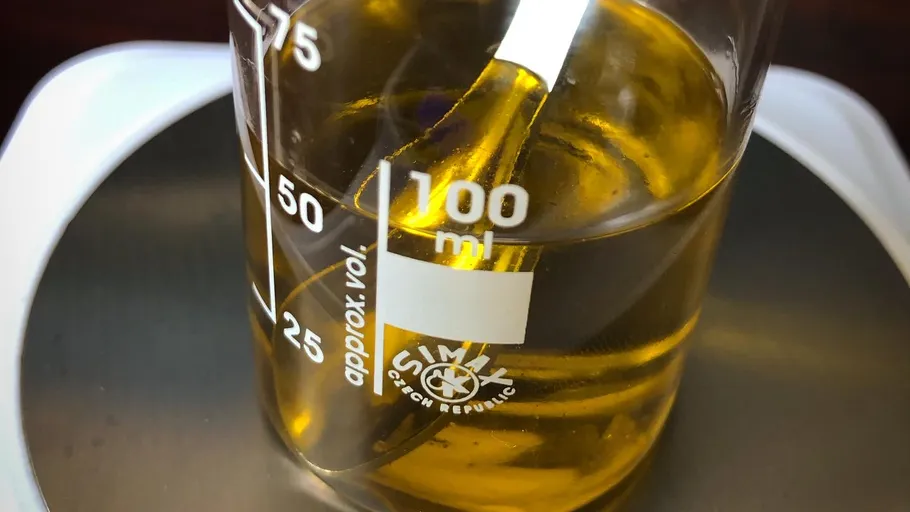 Beaker containing yellow liquid on scale.
