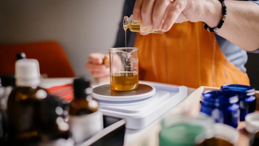 Person pouring liquid into beaker in lab.
