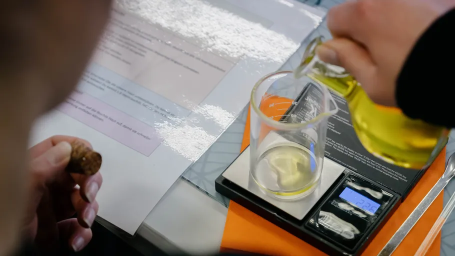 Person pours liquid into beaker on scale.