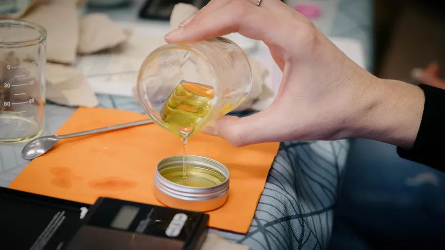 Hand gießt Flüssigkeit in Metallbehälter drinnen.