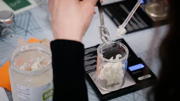 Person measuring cream in laboratory setting.