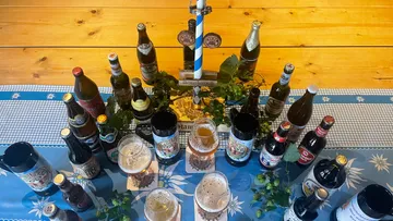 Assorted beer bottles and glasses on table.