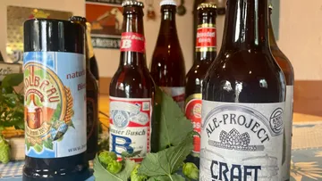 Various beer bottles on a table with hops.