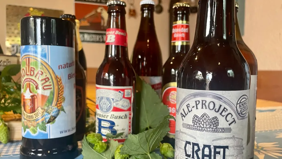 Various beer bottles on a table with hops.
