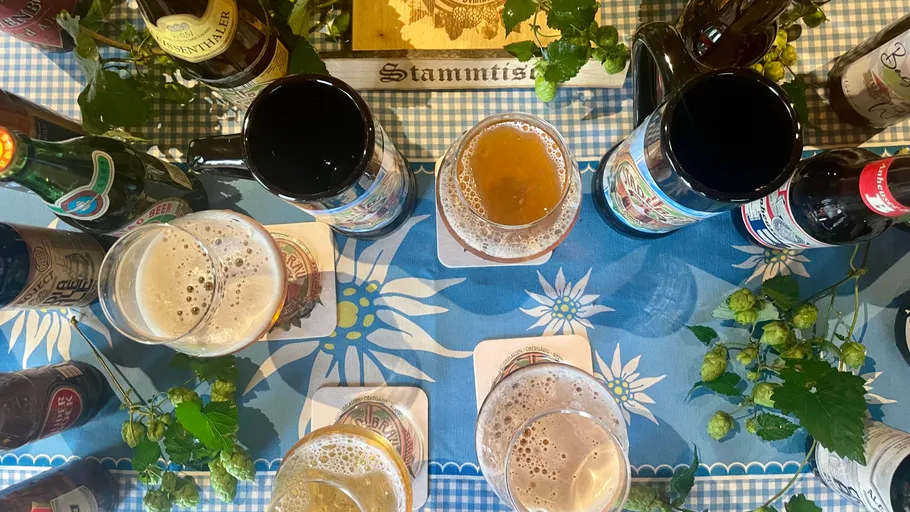 Beers and steins on blue checkered table.