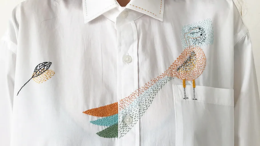White shirt with colorful bird embroidery.