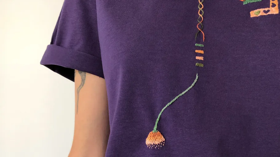 Lila Shirt mit buntem Stickdetail.
