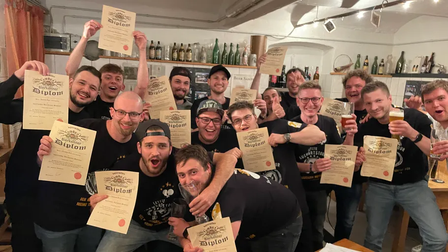 Group celebrating with diplomas and drinks indoors.