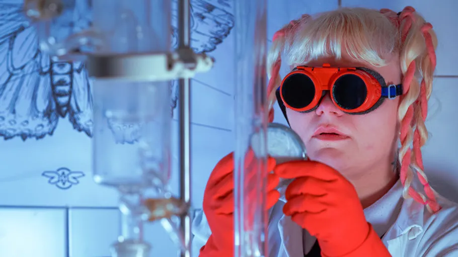 Wissenschaftler untersucht Becher im Labor mit Brille.
