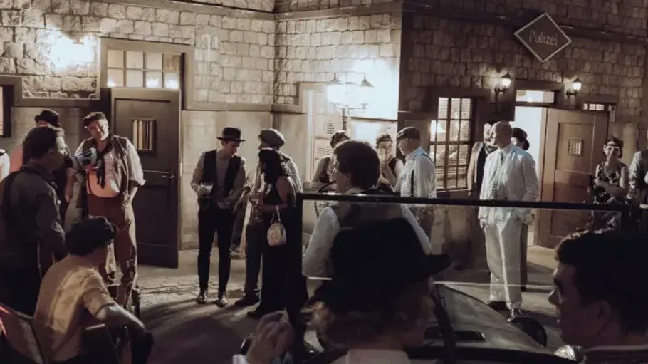 Menschen in Vintage-Kostümen vor Gebäude bei Nacht.