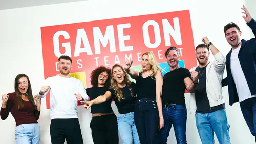 Gruppe jubelt vor einem Schild.