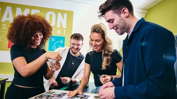 Four people smiling, playing a card game.