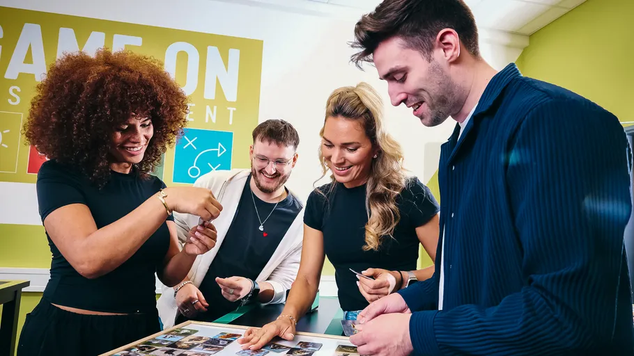 Four people smiling, playing a card game.