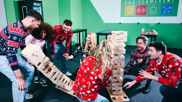 People playing giant Jenga in a festive room.