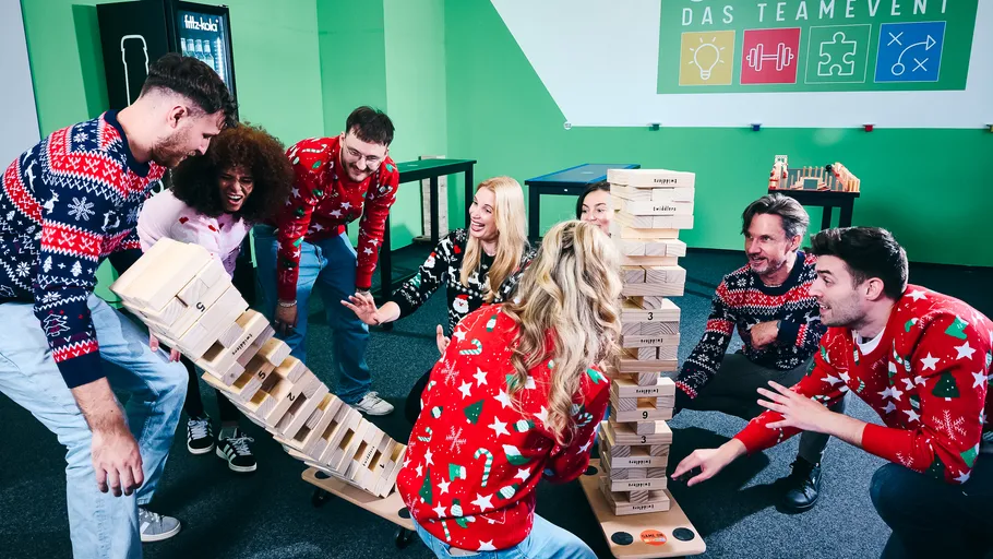 Personen spielen Riesenjenga in einem festlichen Raum.
