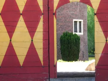 Bunte Tür mit Blick auf einen grünen Busch draußen.