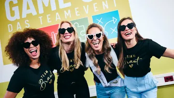 Four women smiling in front of event sign.