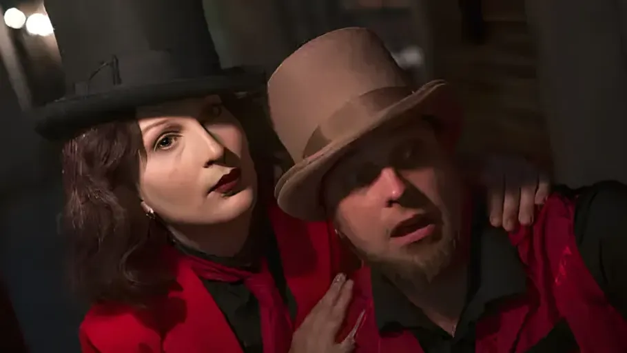 Two people in red jackets wearing hats indoors.