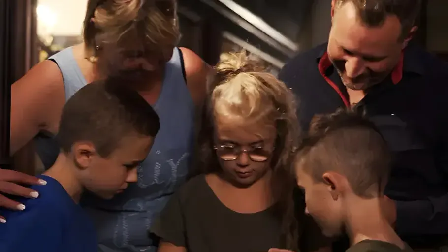 Familie versammelt, betrachtet Smartphone drinnen.