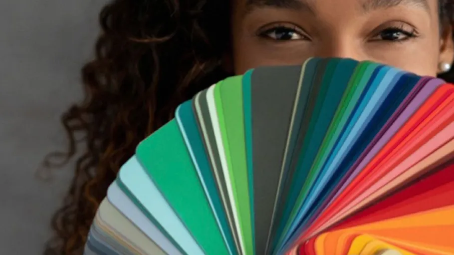 Person holding colorful paint swatches, smiling.
