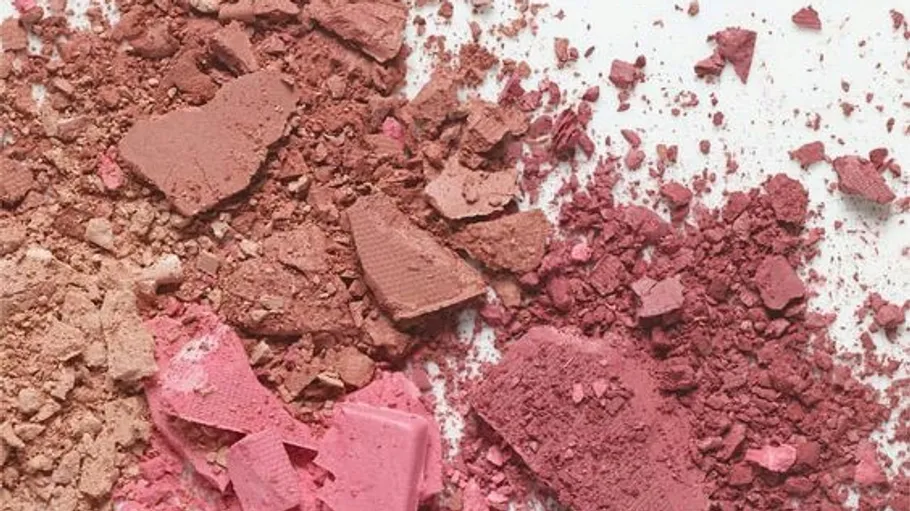 Various colored crushed makeup powders scattered around.